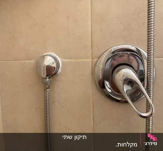 ברז מים וכפתור מתכת על קיר אריחים